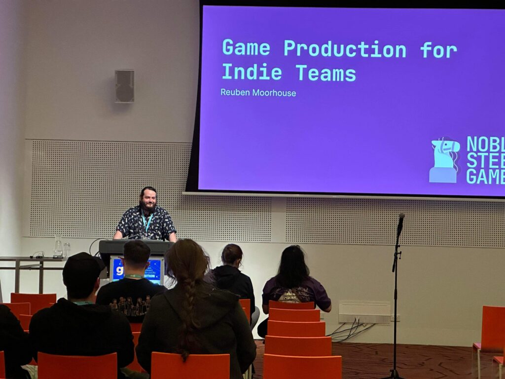 Reuben giving his talk about production by the podium for GCAP 2022.